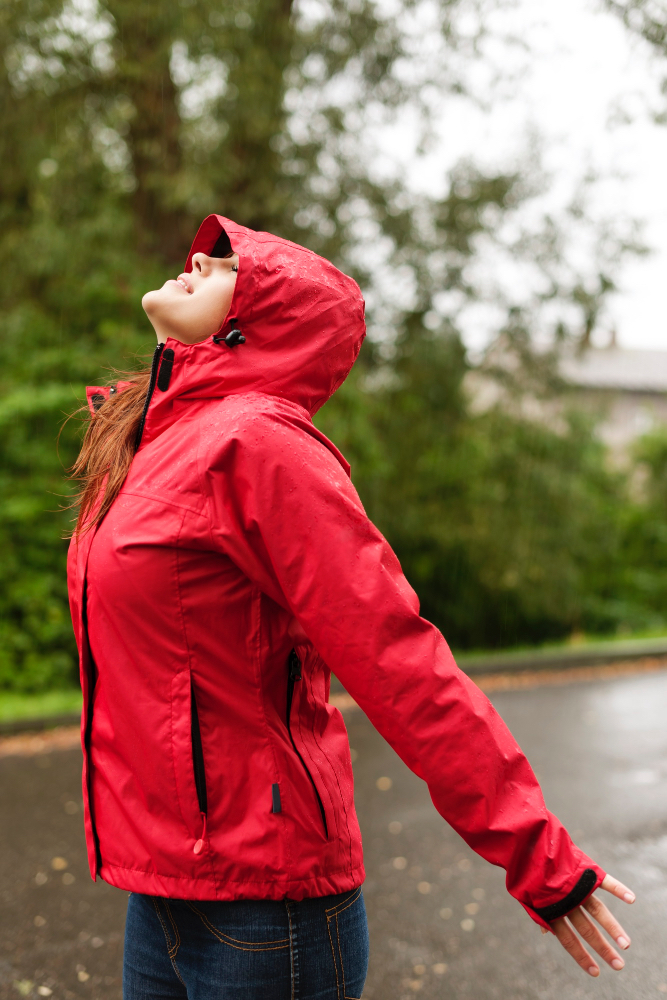 personne heureuse sous la pluie portant un coupe-vent personnalisable rouge