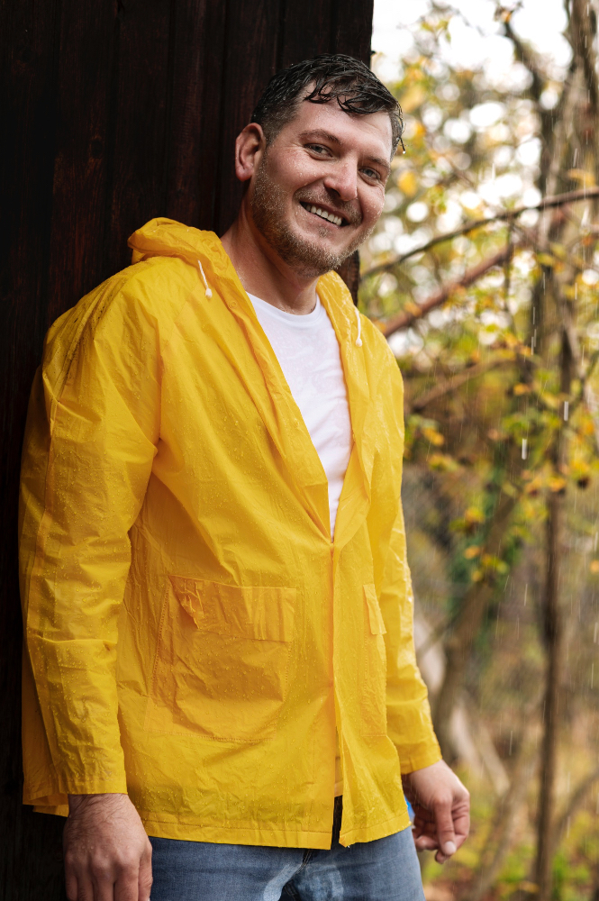 homme souriant portant un coupe vent jaune 